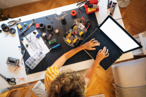 Unrecognizable female programmer and robotic engineer, testing via Arduino platform her prototype of autonomous self-driven robotic car with sensors